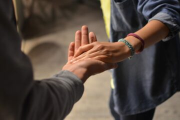 Frau fasst andere Person bei der Hand