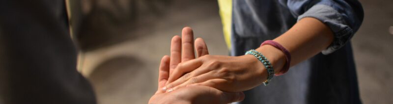 Frau fasst andere Person bei der Hand