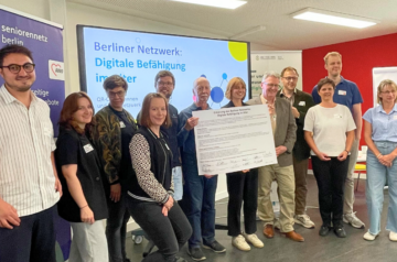 Gruppenfoto der beteiligten Organisationen nach der Unterzeichnung – die Vertreter*innen stehen gemeinsam mit dem unterzeichneten Dokument „Digitale Befähigung im Alter“ in den Händen.