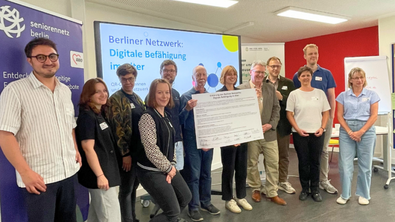 Gruppenfoto der beteiligten Organisationen nach der Unterzeichnung – die Vertreter*innen stehen gemeinsam mit dem unterzeichneten Dokument „Digitale Befähigung im Alter“ in den Händen.