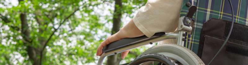 Das Foto zeigt eine ältere Person im Rollstuhl.